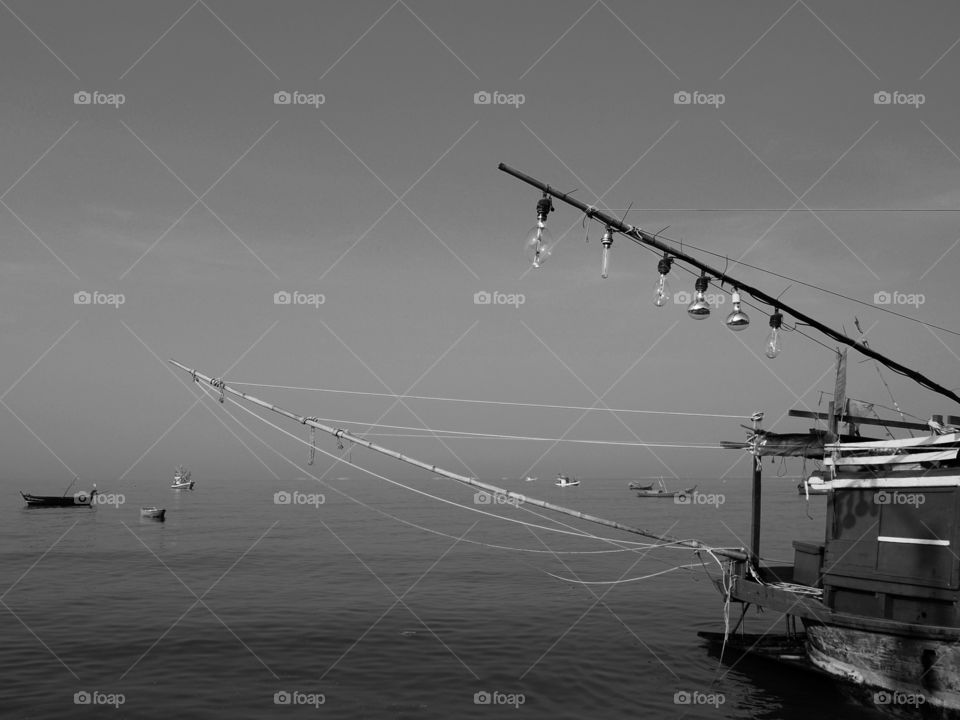 A fishing boat with light bulbs hanging is docked at the bay.