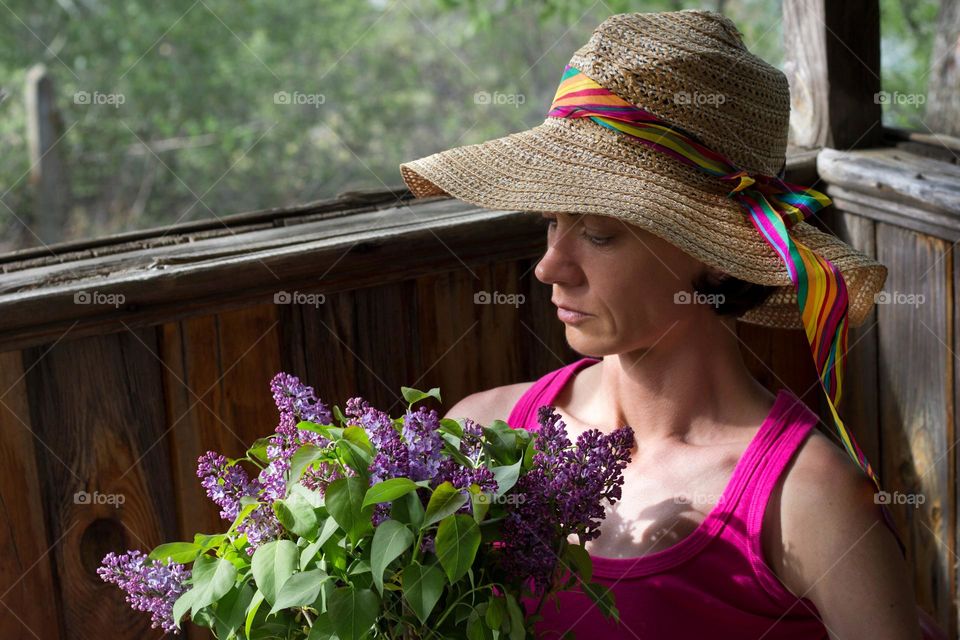 A woman holds lilac flowers at the balcony