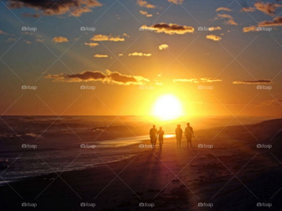 A walk on the beach. Friends walking the beach during an amazing sunset 