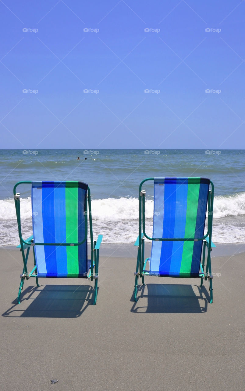 Beach chairs. Two beach chairs sitting beside the surf