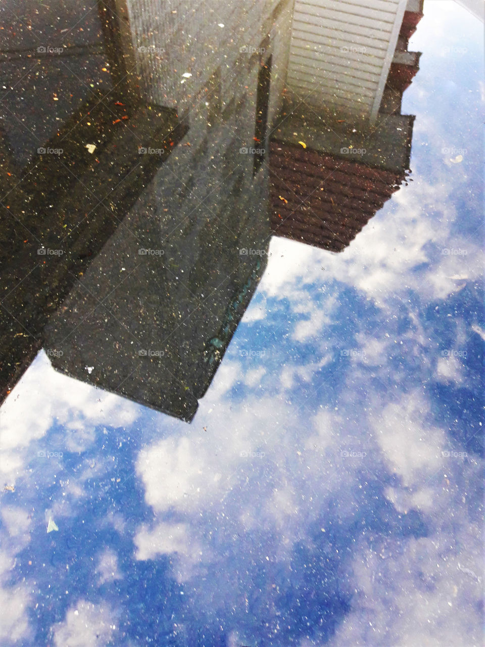 Reflection of the sky and a building in a puddle.