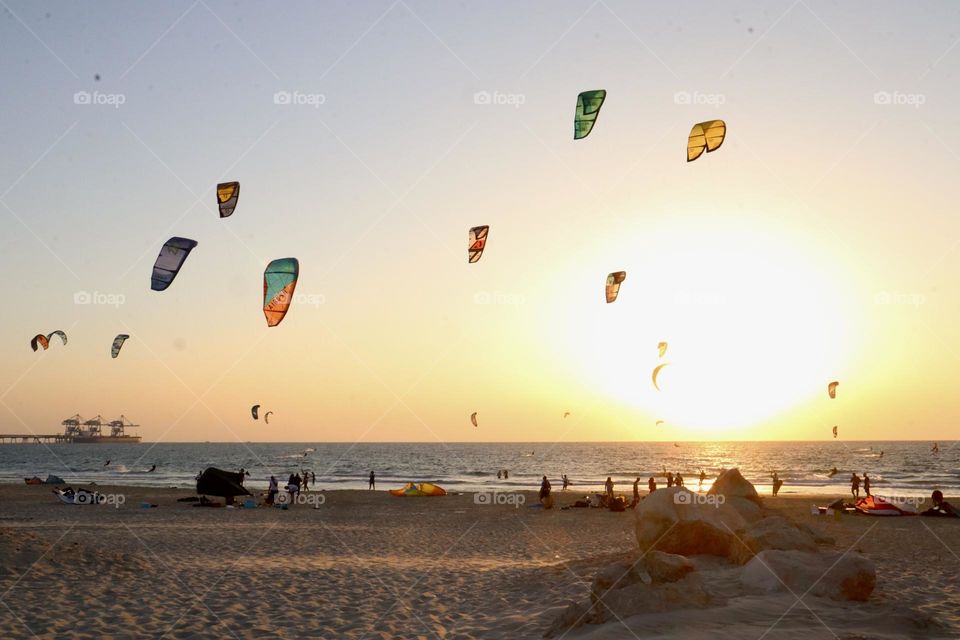 Many kitesurfing kites in sunset sky on the beach