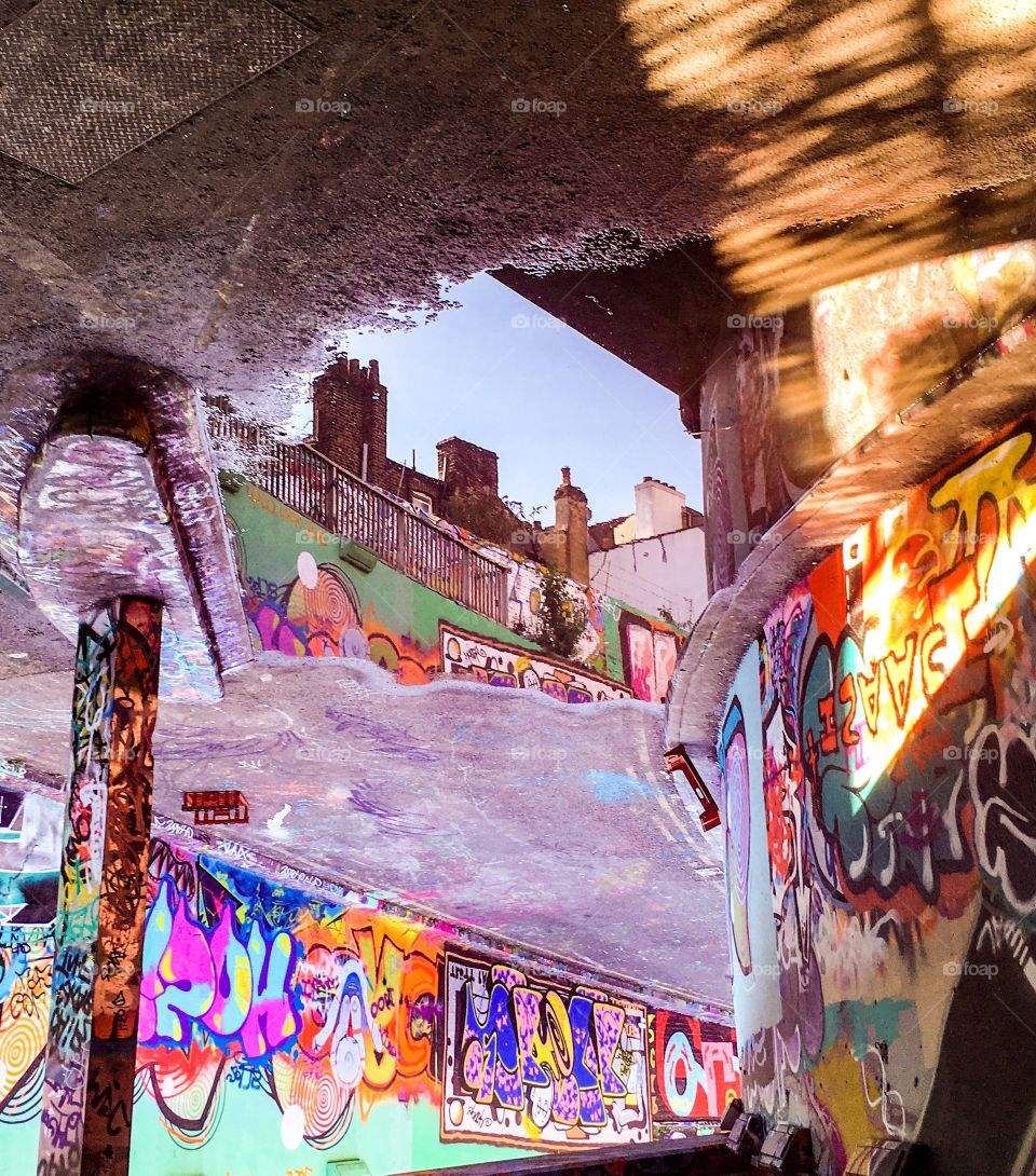 Cityscape reflected in puddle on graffiti covered street scene 