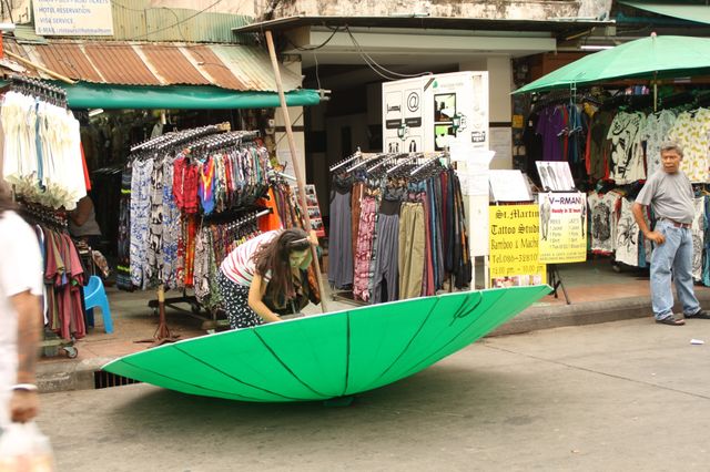 Gigant umbrella. I was walking through the market and saw this woman fighting with the gigant umbrella while the man was just looking