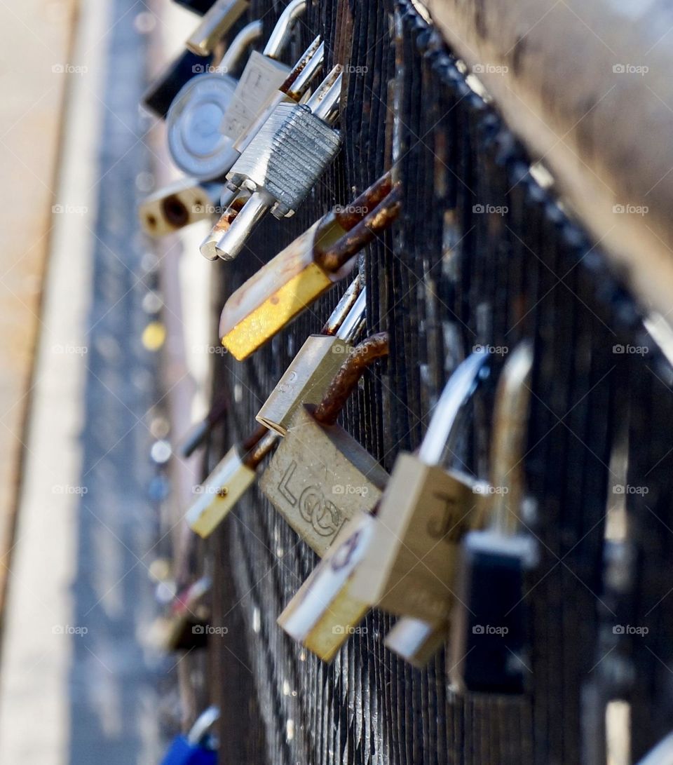 A closeup of love locks on a fence.