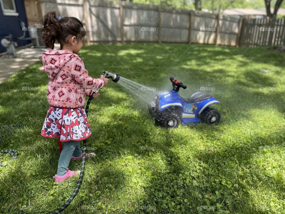 Child spraying off toy vehicle, toddler helps clean up, toddler loves cleaning, keeping her toys neat and clean 