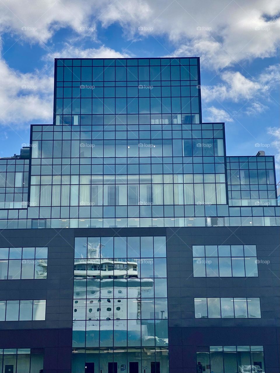 The reflection of a cruise ship in the windows of a tall building
