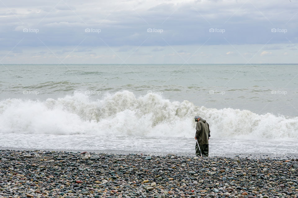 a man with a metal detector walks along the beach, treasure hunter