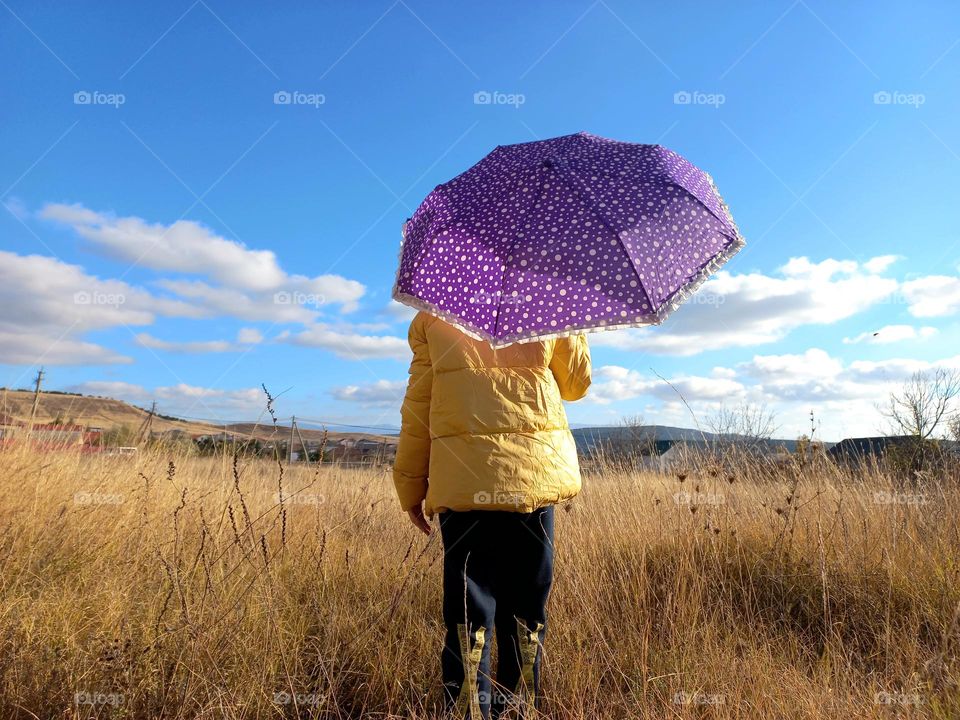 girl holding purple umbrella with white polka dots.