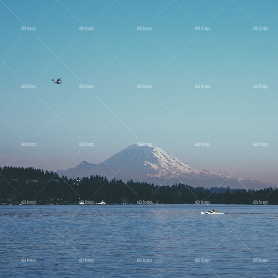 Mount Rainer and Lake Washington . View of Mount Rainer from Lake Washington with kayaker and plane during sunset 