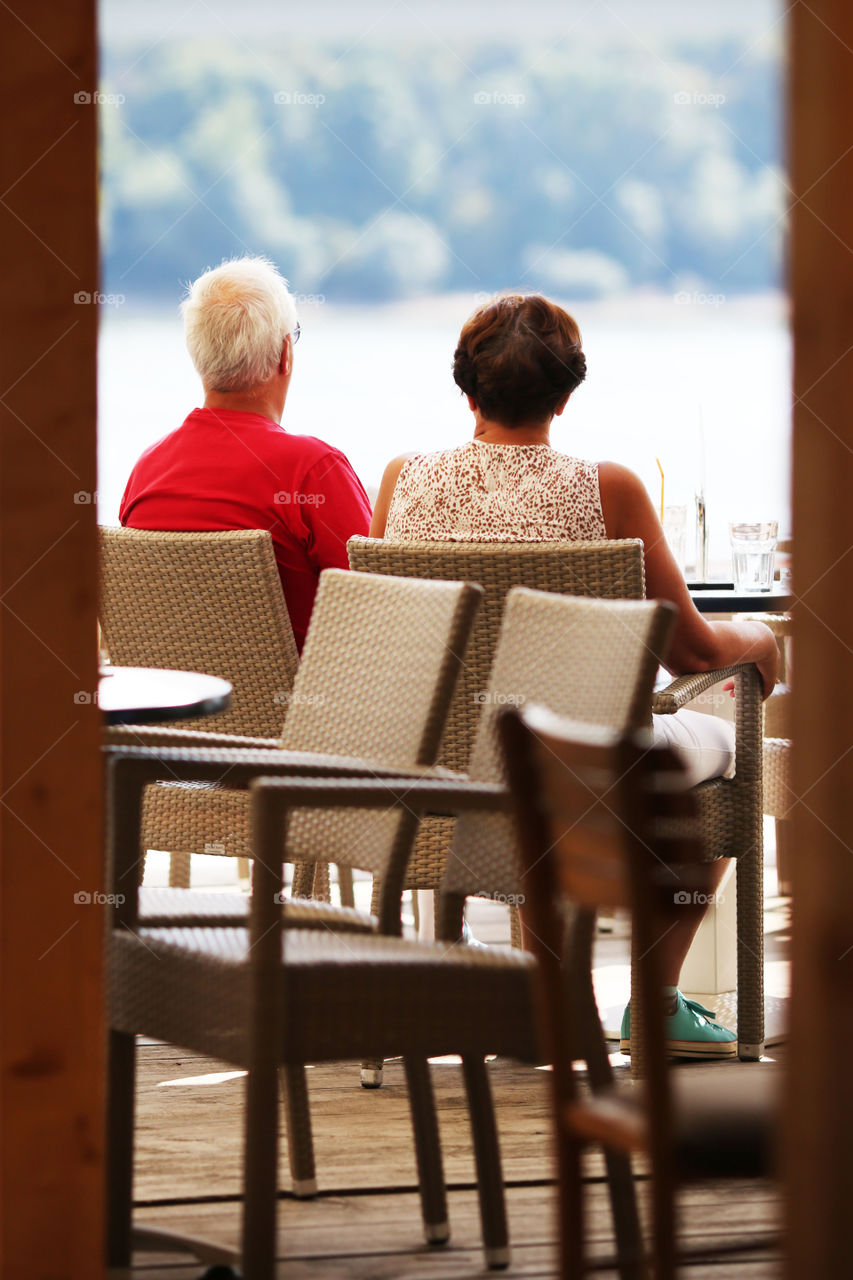 Older couple enjoying the view from the shades of cafe