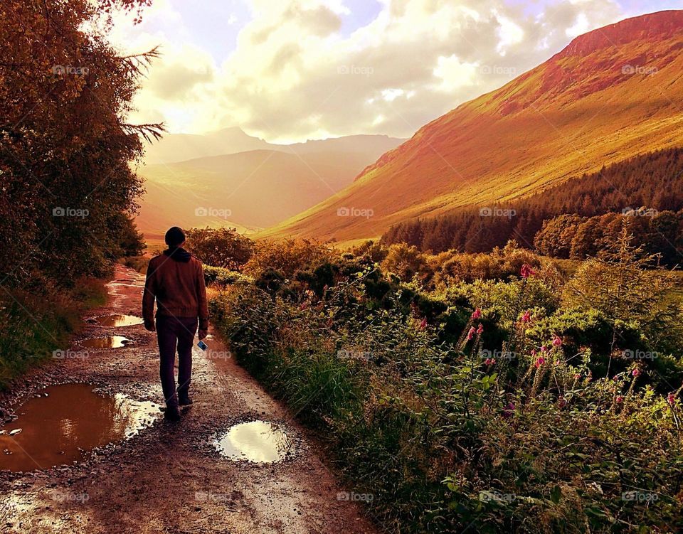 A man takes a walk after the rain, towards the cloudy hills on the Isle of Arran, Scotland.
