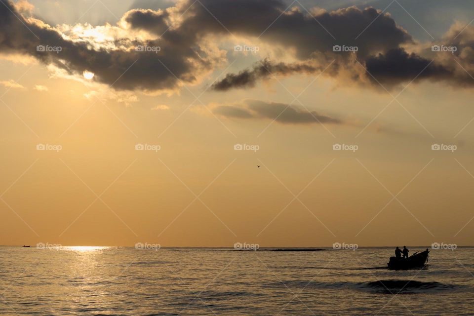 Sunset at the sea with fishermen boat