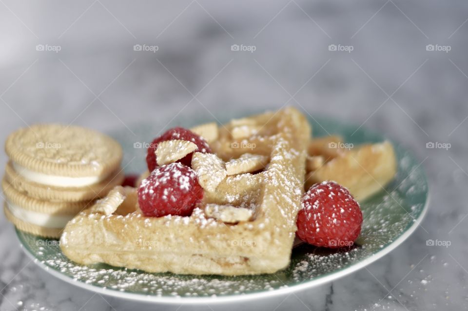 Golden double stuff Oreo cookies and a waffle with raspberries and powdered sugar