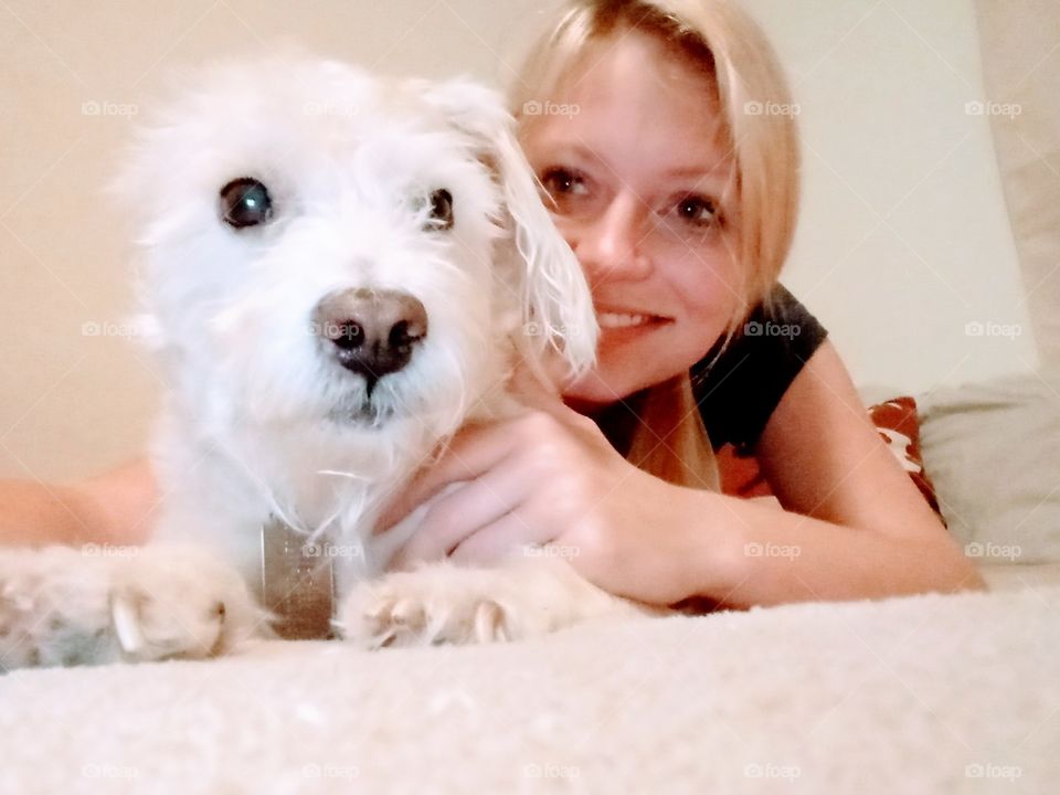 young woman taking a selfie with her cute small white dog