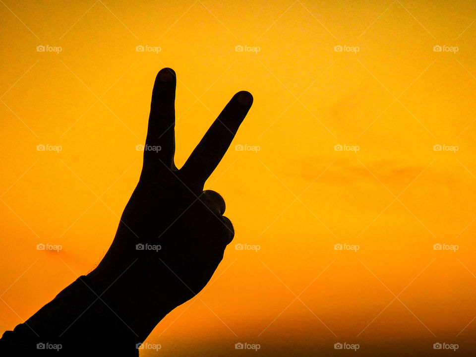 Silhouette image or wallpaper - This photograph shows Victory in whole year. It is hand posture with after sunset golden light.