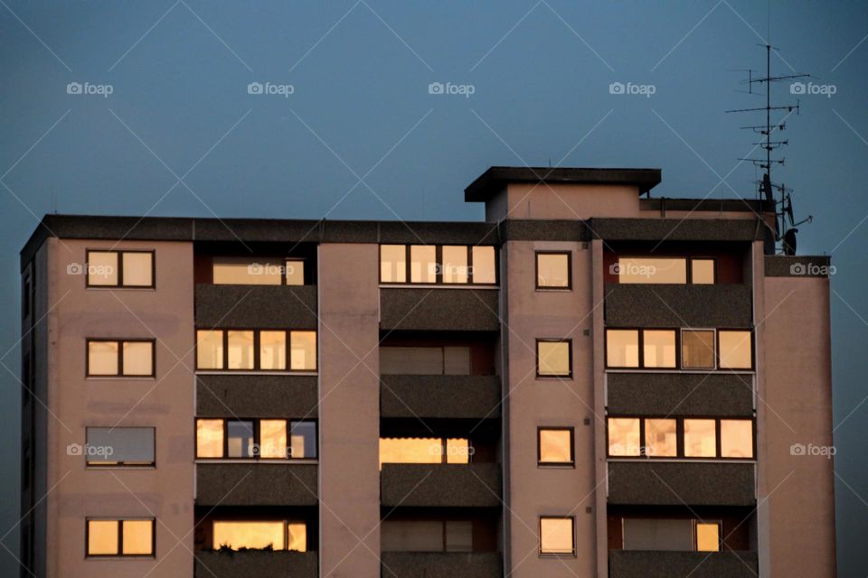 Reflections of the golden sunset in the windows of a building at blue hour