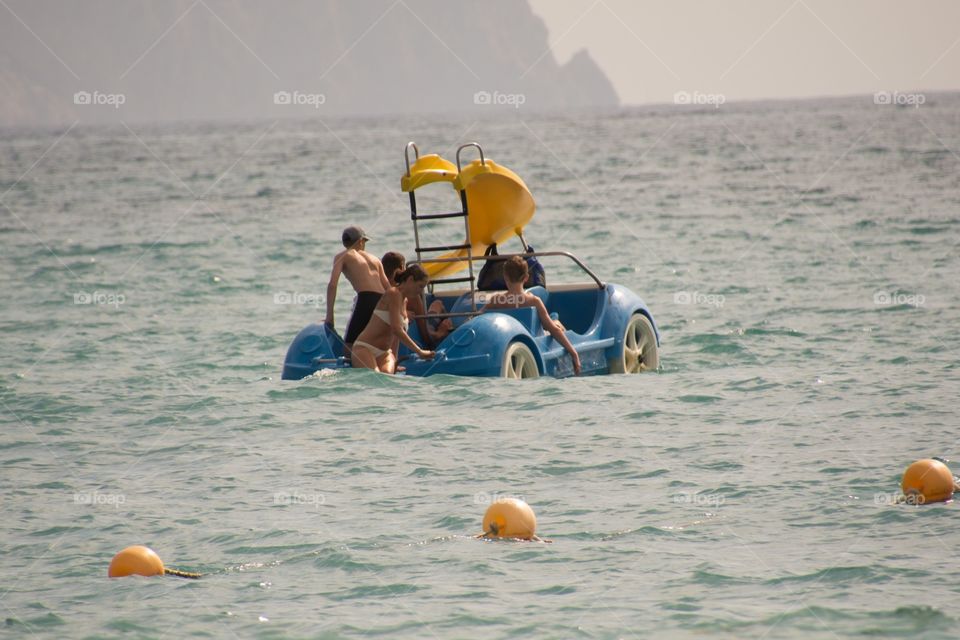 Teenagers enjoying a ride in the car boat with slider in the middle of the ocean in Spain