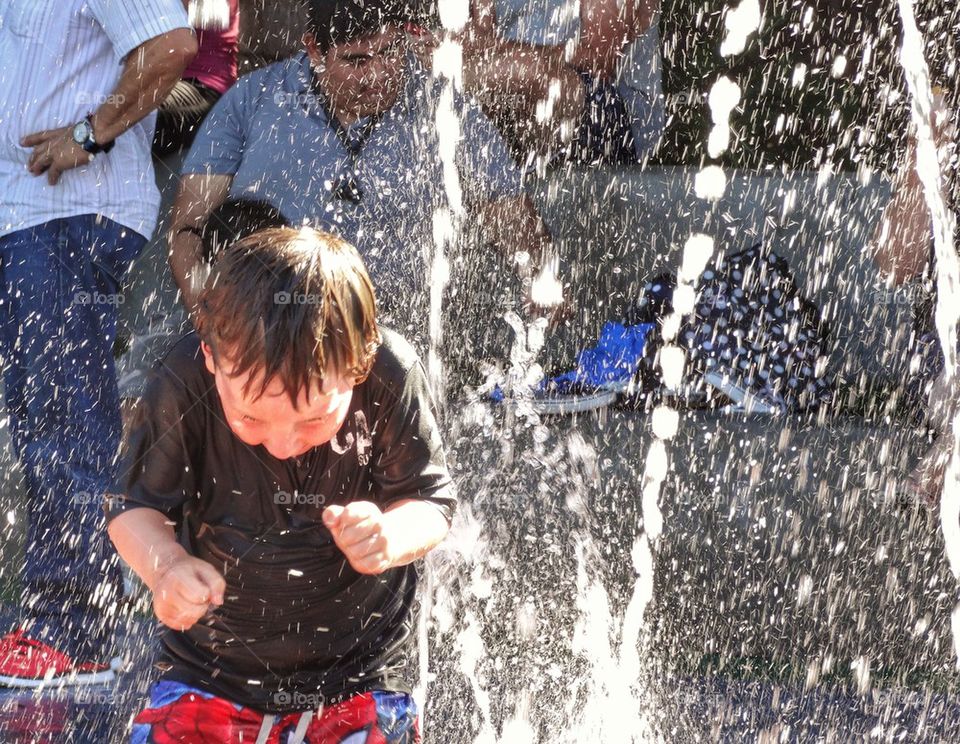 Boy Splashing In Water Fountain