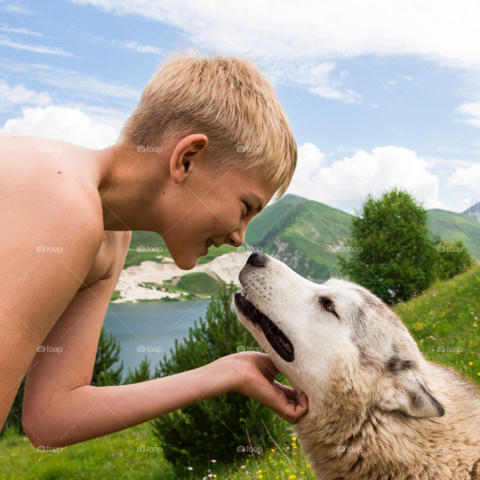 Shirtless boy playing with dog