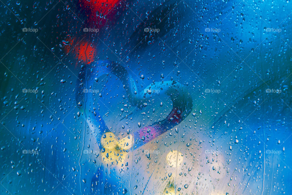 Heart in a rainy window with bokeh city lights at night