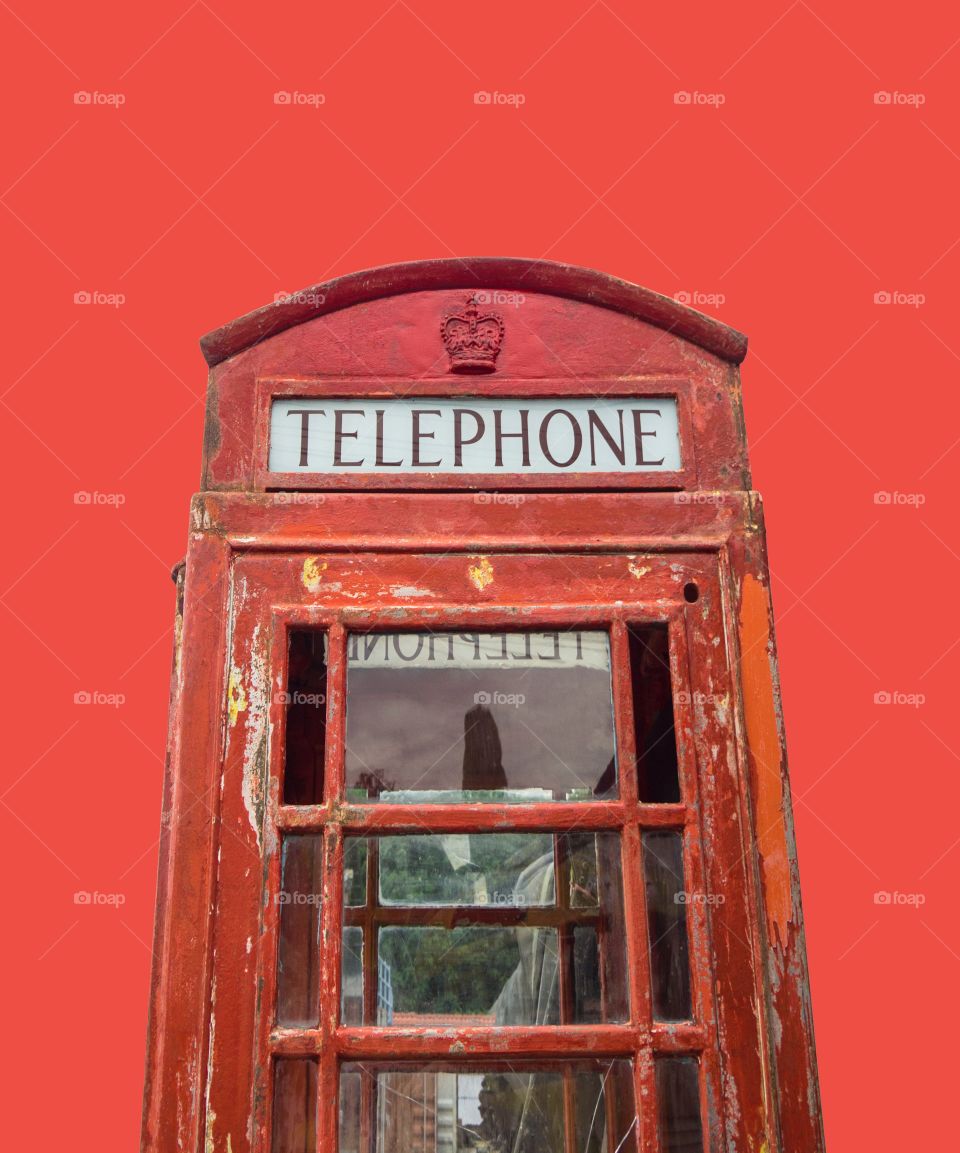 Red old British telephone booth isolated on red background