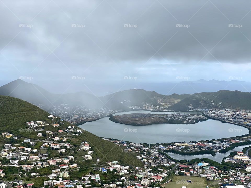 The view from a mountain top as rain moves in across mountains and a harbor