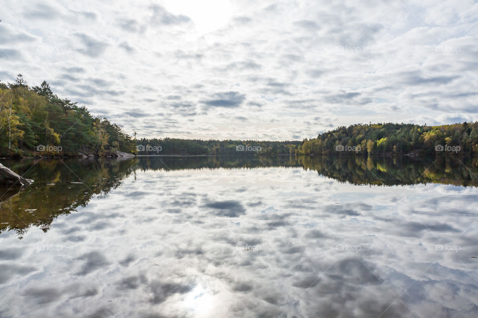 Forest in autumn colors and sky reflection in mirror lake 