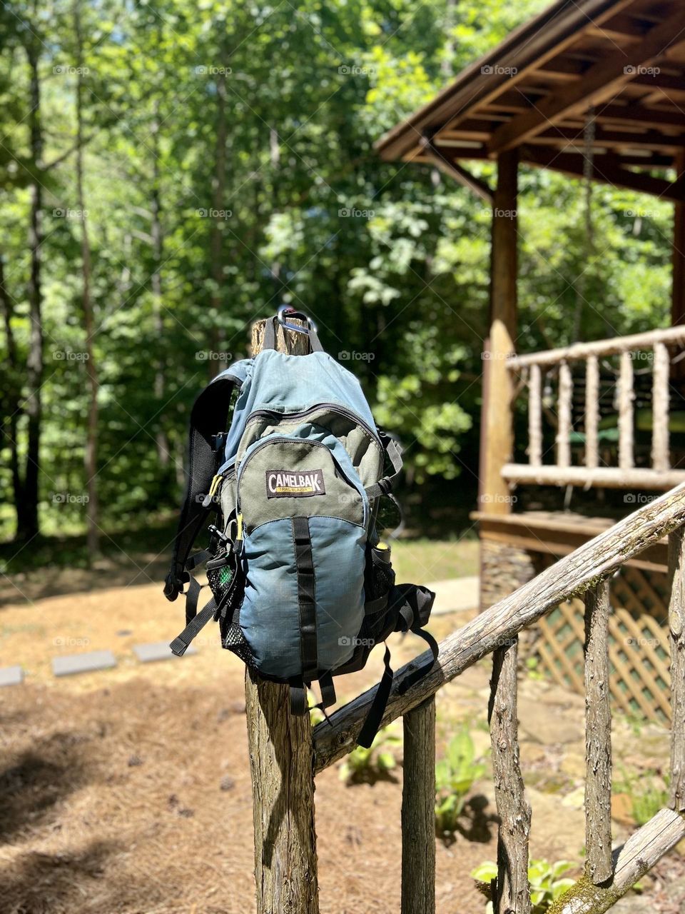 Blue backpack hanging on post of forest cabin. Ready for a day of hiking and exploring.