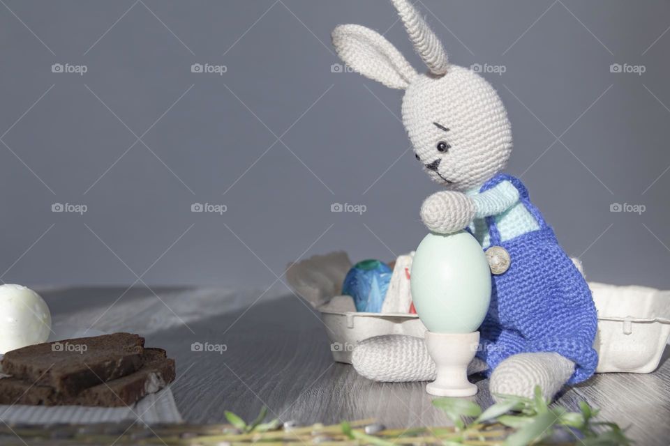 The rabbit of blue color is knitted by own hands at home.  Easter Bunny and chicken egg on coasters.  Craft product.