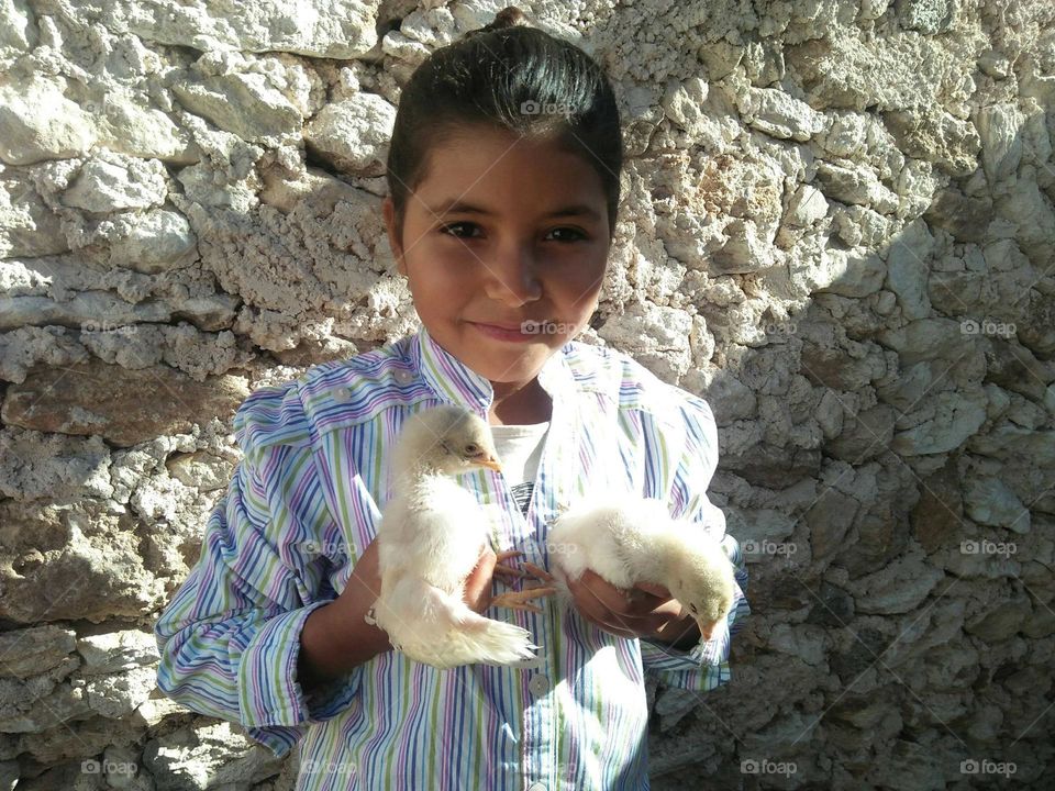 A beautiful girl holding two small Chikens.