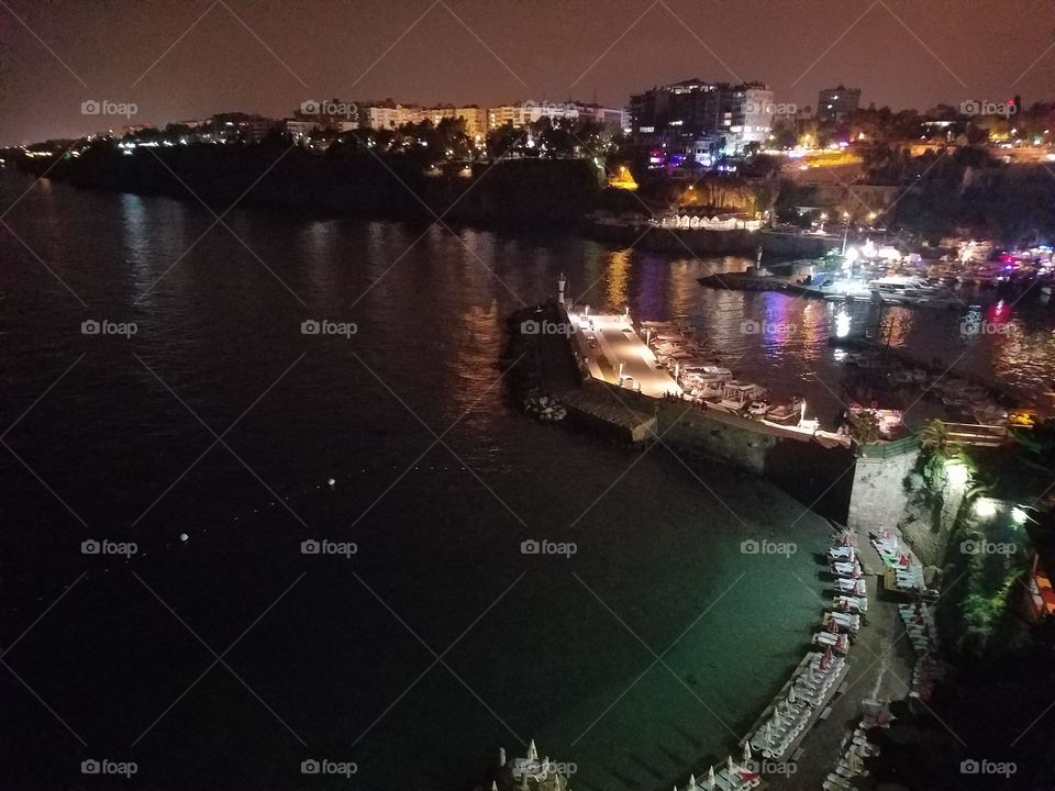 night shot, top view of the harbor and hidden beach with the city reflecting from off the water in old town antalya turkey