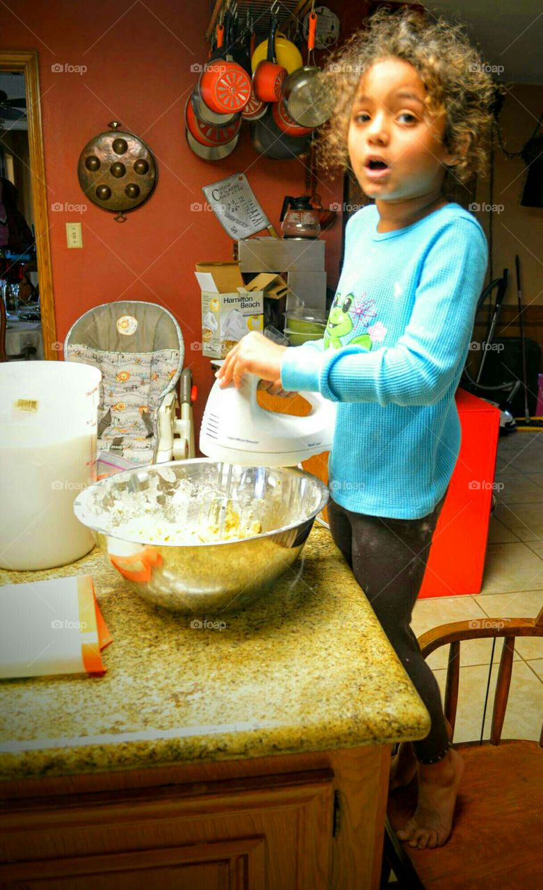 Child making cookies in the kitchen by herself.