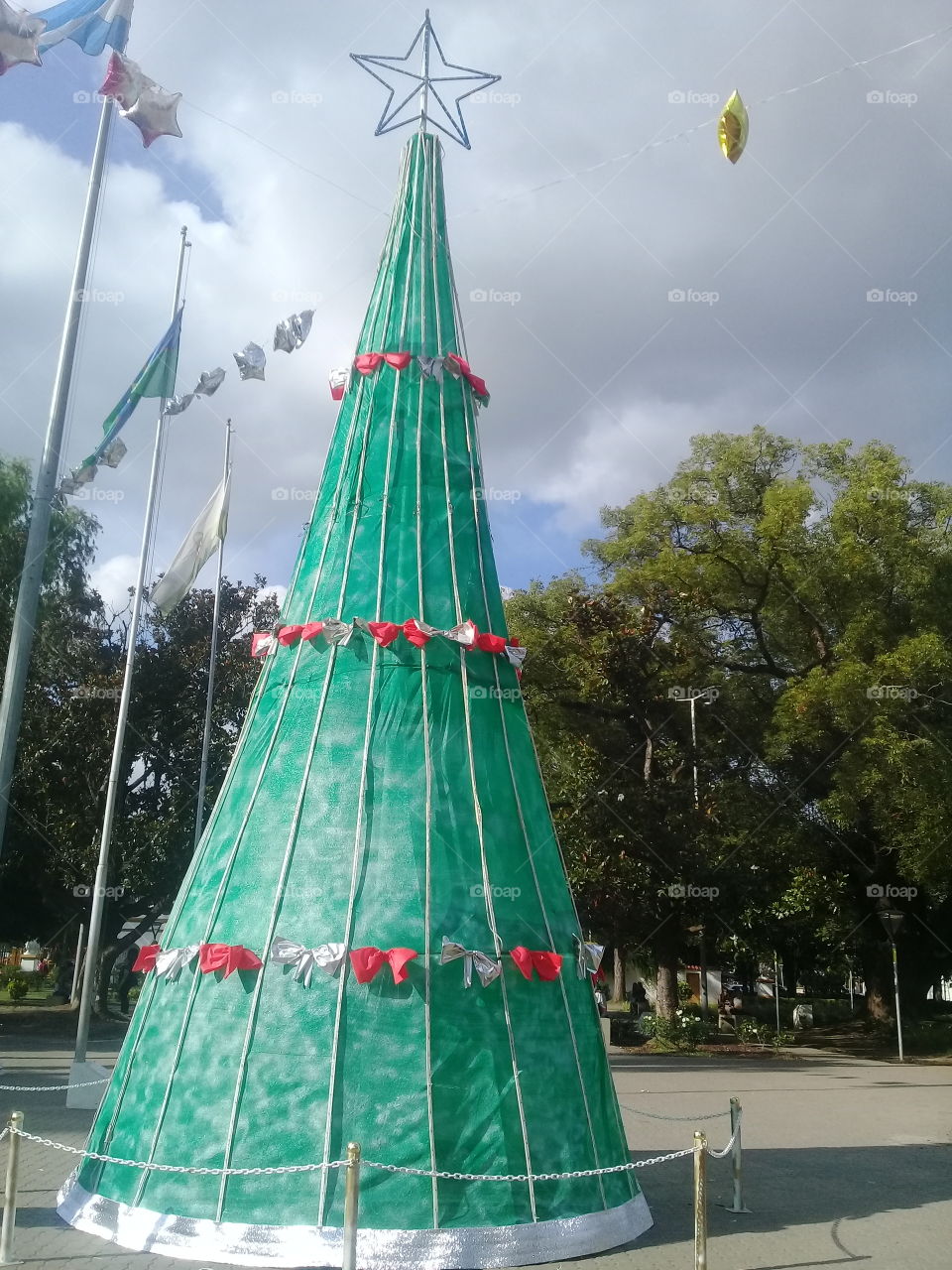 árbol de navidad de madera gorrado con lona verde y adornos navideños de guirnaldas.