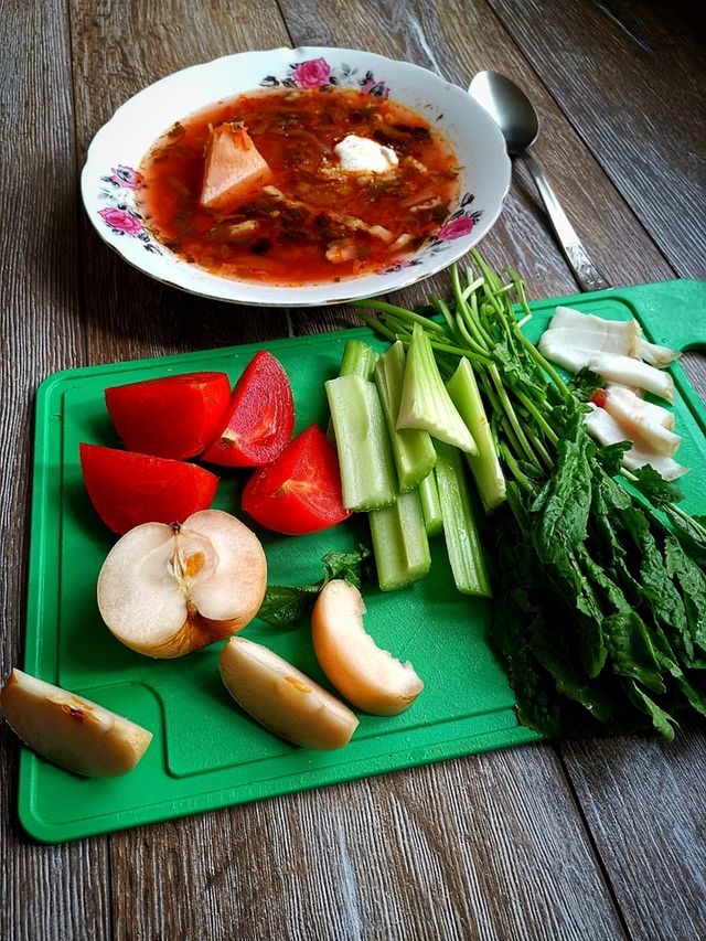 A plate of borscht and chopped fruits, vegetables, bacon