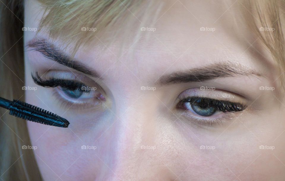 woman paints her eyes with mascara