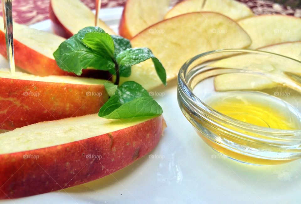 Cut apples with honey and mint is on a plate. Breakfast in the restaurant with an apple, honey and mint in white plate