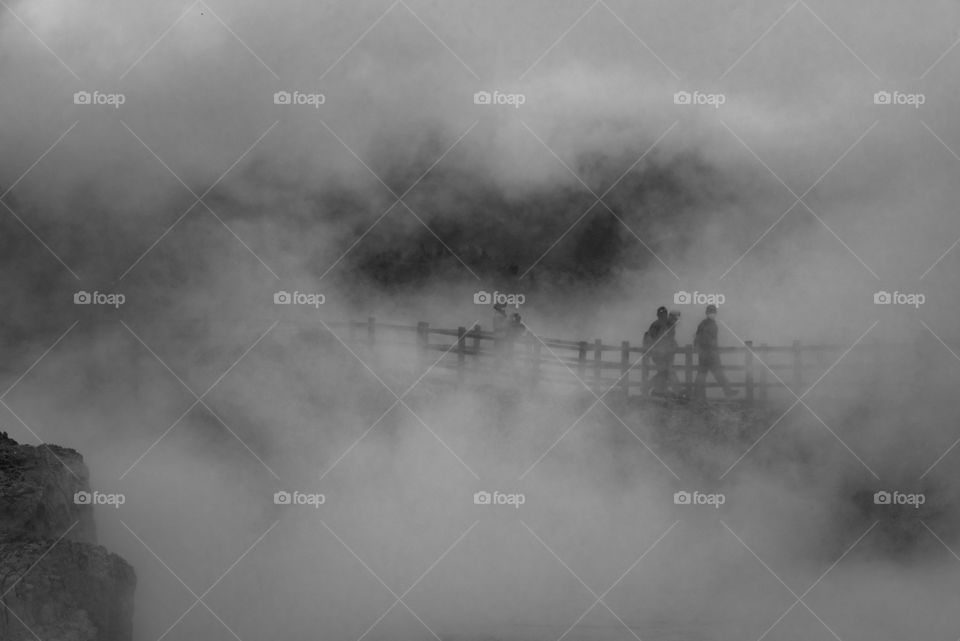 Heavy and dramatic smoke almost covers the visitors of Sikidang crater in Banjarnegara district, Central Java, Indonesia, who walking through the bridge