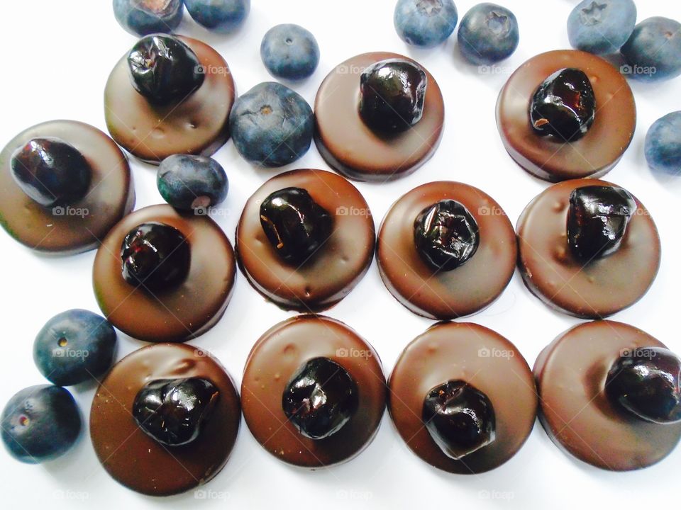 Round pieces of chocolate with blueberries on white background 