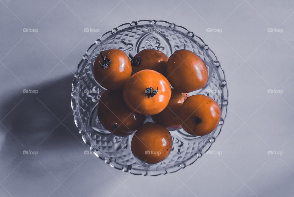 some tomatoes in a glass container on a white background