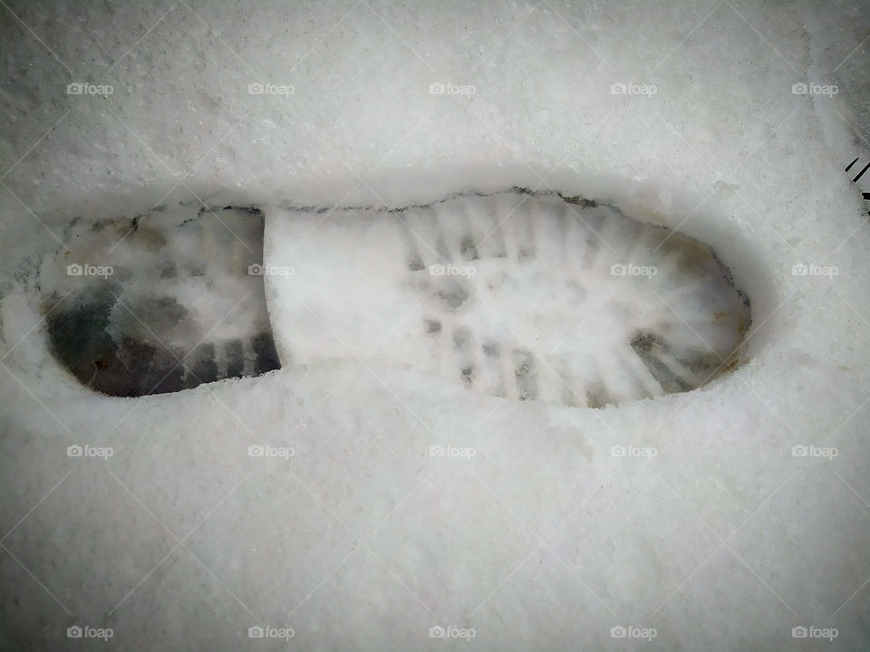A footprint in the snow from a boot