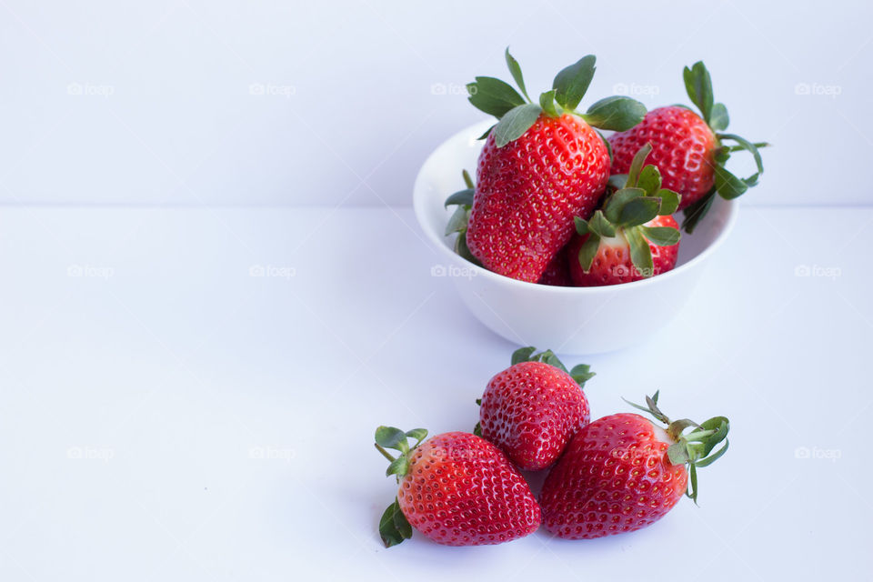 Groups of strawberries. A group of strawberries and a bowl of strawberries on a white background