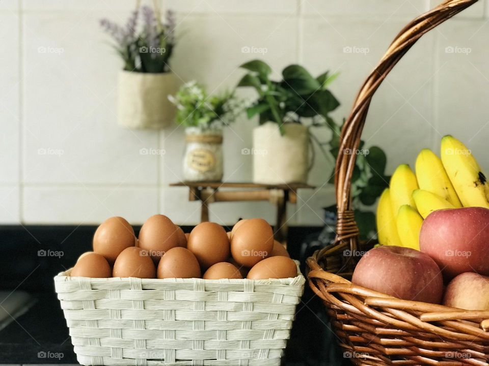 A basket full of egg and fruits on kitchen cabinet for good health and for staying fit .