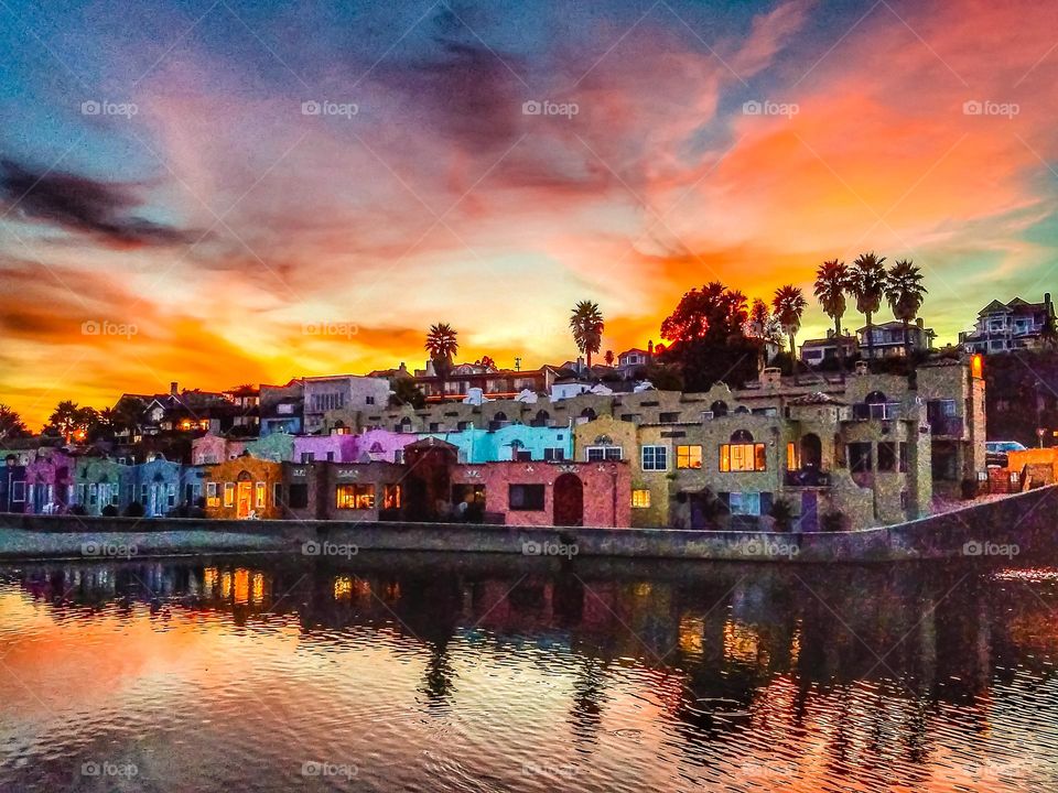 A beautiful sunset in Capitola California on the beach with the famous colorful Venetian condominiums with the reflection of the stunningly vibrant dusk sky on the Soquel River on  the Monterey Bay 