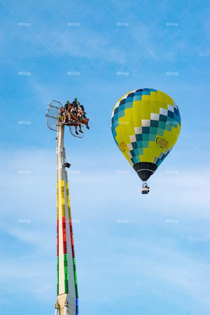 thill seekers hot air balloon passing near funfair ride