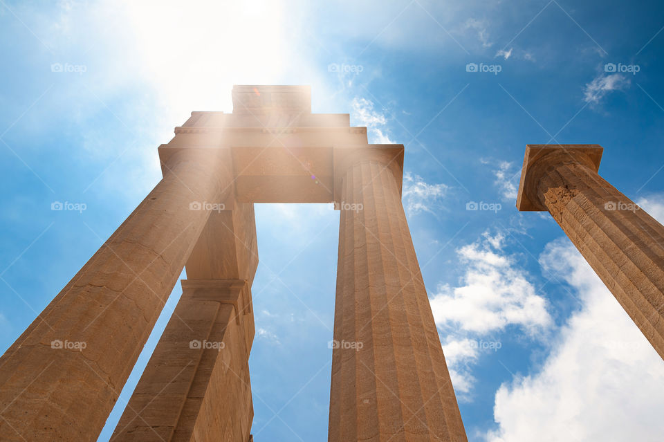 Ancient Greek columns in Doric order against blue sky and sunlight.
