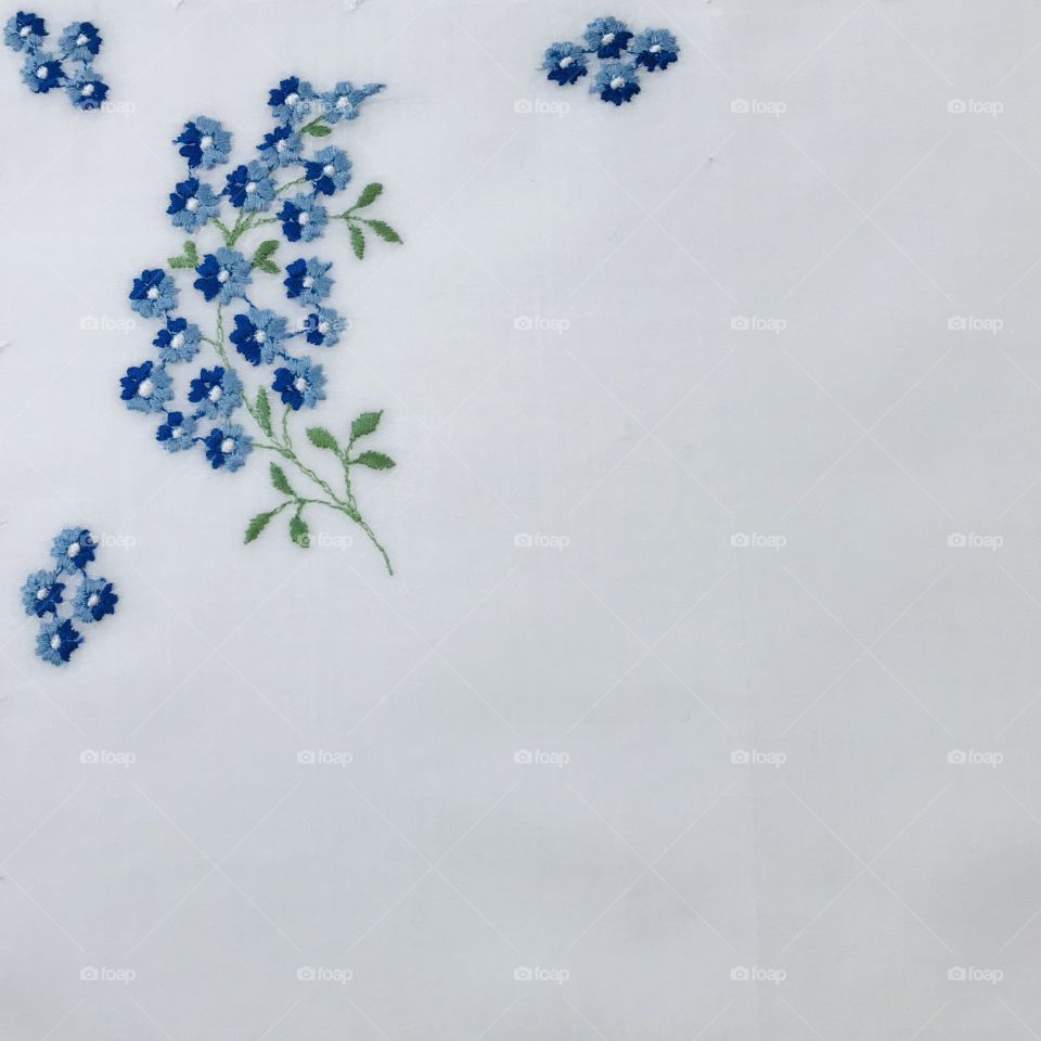 Beautiful two tone blue little flowers hand embroidery embroidered floral design with blank plain solid white empty background 