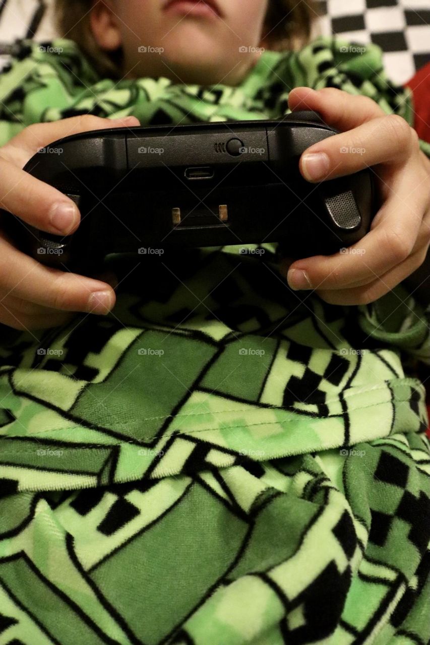 Playing video games. Holding Xbox controller on green Minecraft pyjama background 