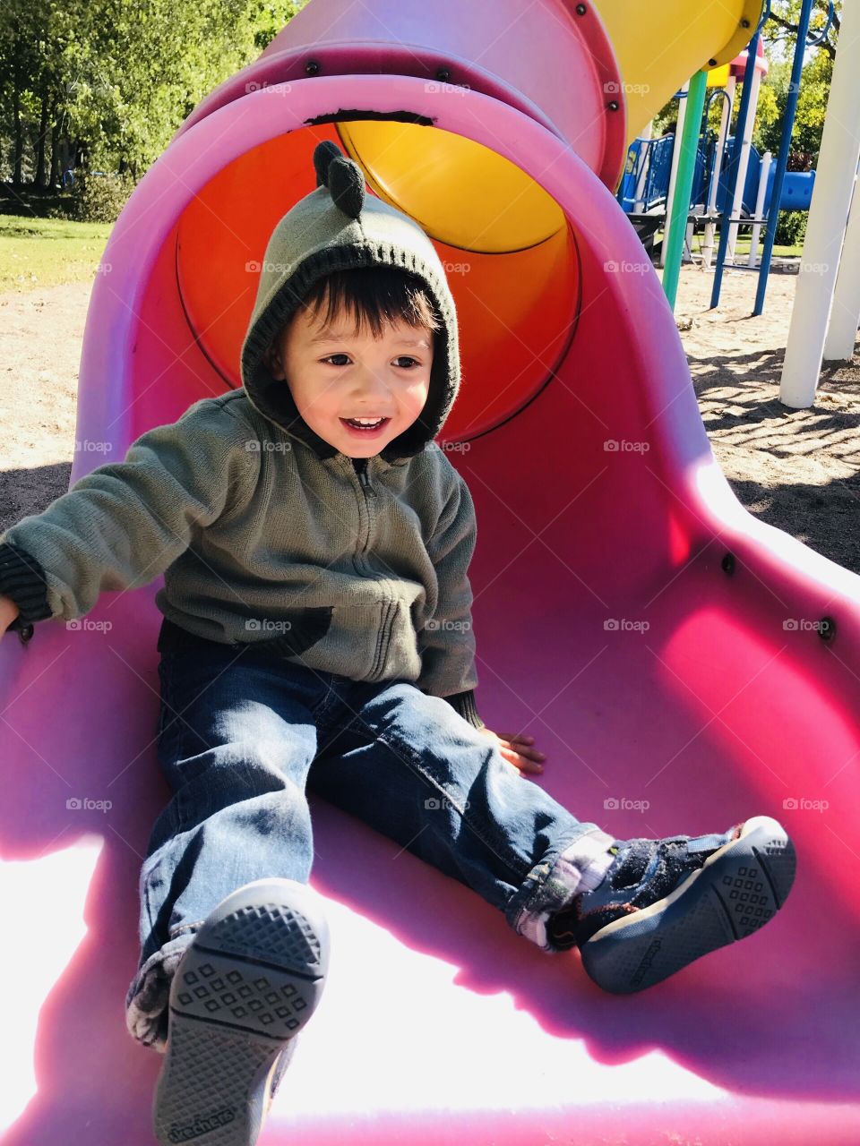 Young child coming down a colourful slide