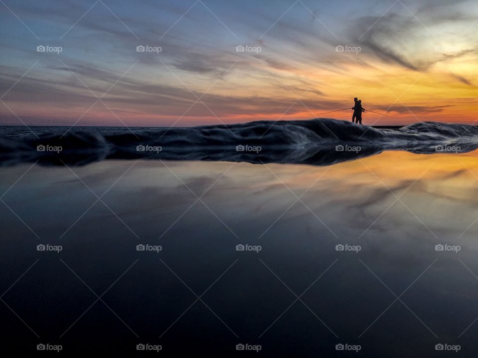 Silhouettes or fishermen fishing at sunset. 